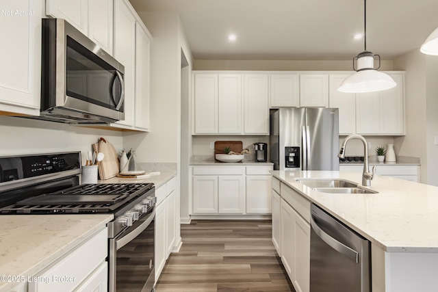 kitchen featuring stainless steel appliances, white cabinetry, sink, and decorative light fixtures