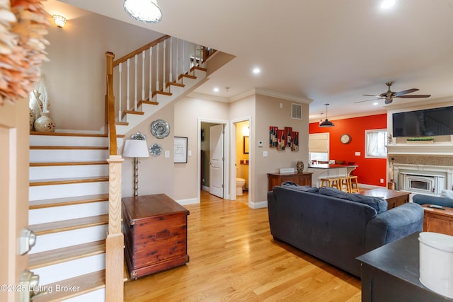 living room featuring ceiling fan, ornamental molding, and light hardwood / wood-style flooring