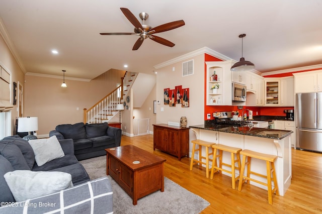 living room with crown molding, sink, ceiling fan, and light wood-type flooring