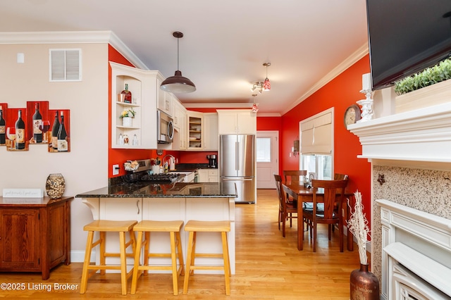 kitchen featuring a breakfast bar, crown molding, hanging light fixtures, appliances with stainless steel finishes, and kitchen peninsula