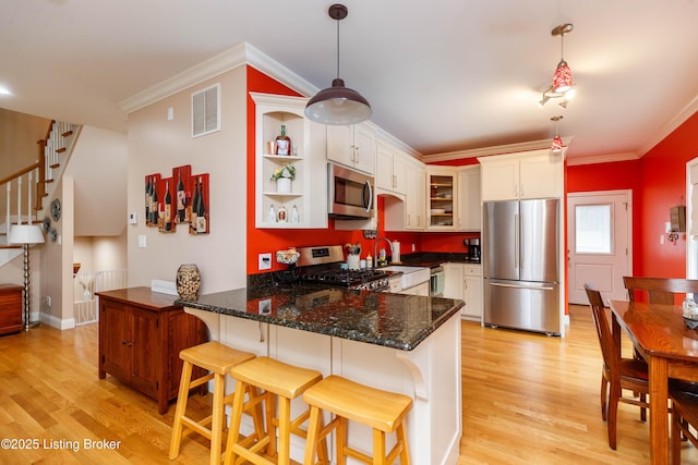 kitchen with light hardwood / wood-style flooring, hanging light fixtures, stainless steel appliances, white cabinets, and kitchen peninsula