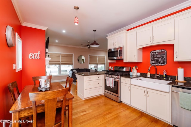 kitchen with appliances with stainless steel finishes, decorative light fixtures, white cabinetry, sink, and kitchen peninsula