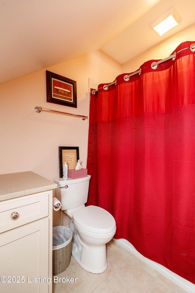 bathroom with lofted ceiling, vanity, tile patterned floors, and toilet