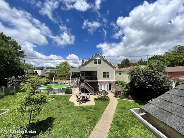 rear view of house featuring a fenced in pool, a patio, and a lawn