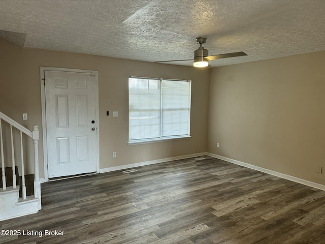 foyer entrance with ceiling fan, dark wood-type flooring, and a textured ceiling