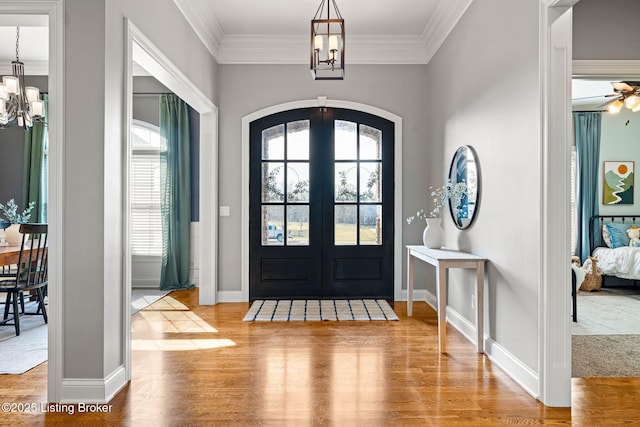 foyer featuring french doors, crown molding, a chandelier, and hardwood / wood-style floors