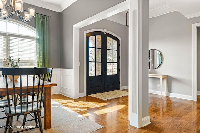 entrance foyer featuring wood-type flooring, ornamental molding, and french doors