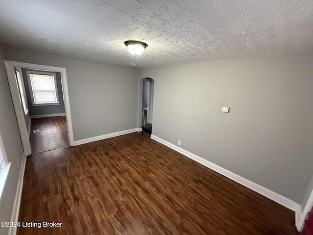 unfurnished room with dark wood-type flooring and a textured ceiling