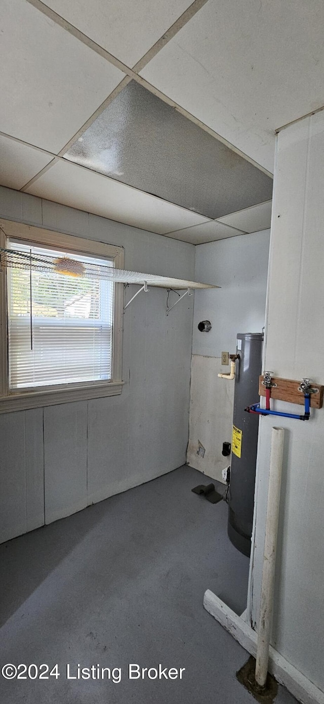 basement featuring water heater and a drop ceiling