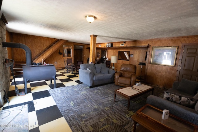 living room with a wood stove, a textured ceiling, and wood walls