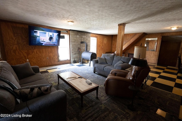 living room with a wood stove, a textured ceiling, and wood walls