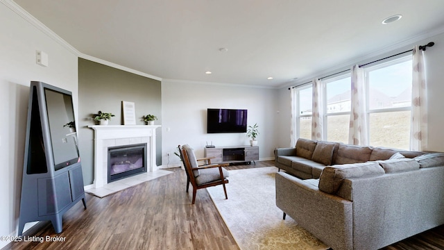 living room with hardwood / wood-style flooring, ornamental molding, and a tiled fireplace