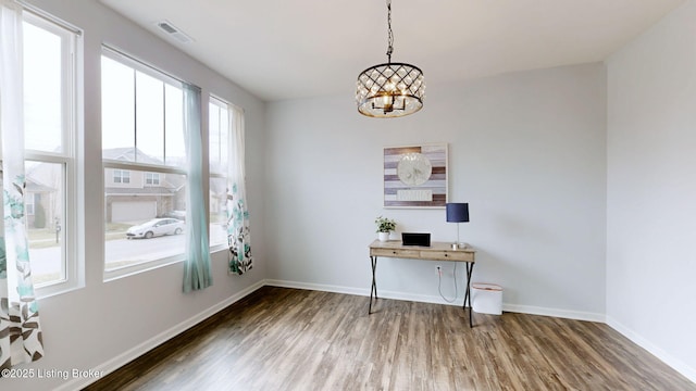 unfurnished office with dark hardwood / wood-style flooring and an inviting chandelier