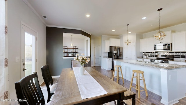 dining space with ornamental molding, sink, and light hardwood / wood-style floors