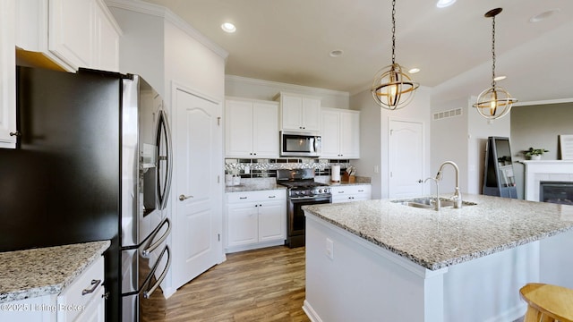 kitchen featuring sink, appliances with stainless steel finishes, white cabinetry, hanging light fixtures, and light stone countertops