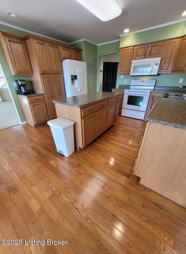 kitchen with sink, light wood-type flooring, ornamental molding, a kitchen island, and white appliances