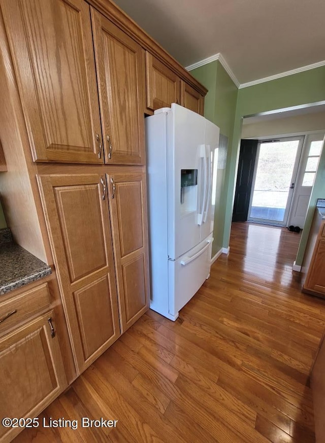 kitchen featuring crown molding, white fridge with ice dispenser, and light hardwood / wood-style floors