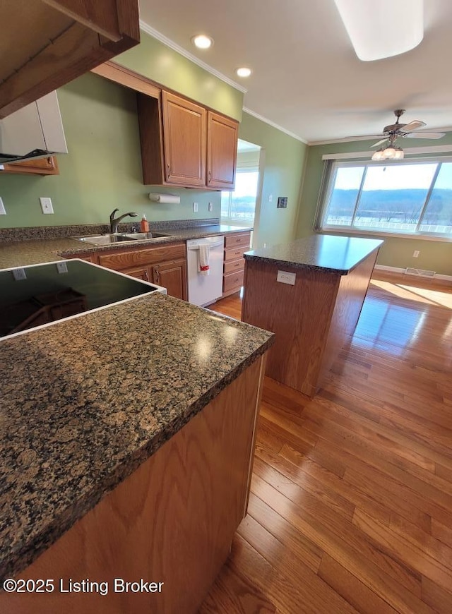 kitchen with ornamental molding, a center island, dishwasher, and light hardwood / wood-style flooring