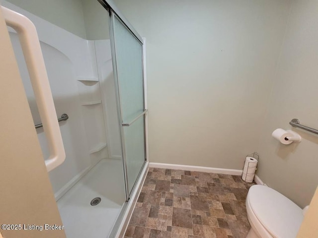 bathroom featuring a shower with shower door and toilet