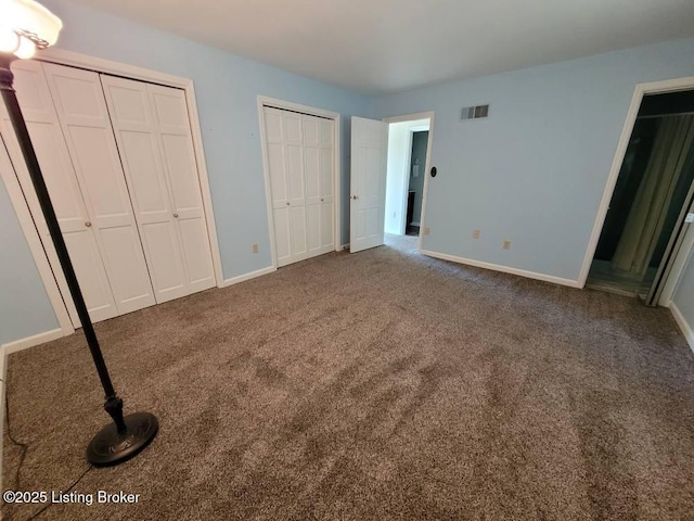 unfurnished bedroom featuring carpet floors and two closets