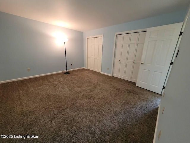 unfurnished bedroom with multiple closets and dark colored carpet