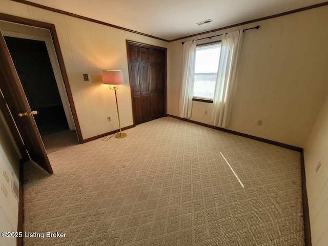 unfurnished bedroom with ornamental molding, light colored carpet, and a closet