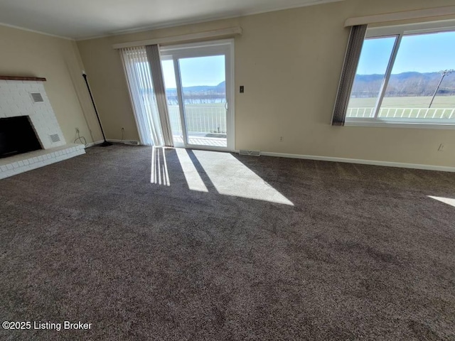 unfurnished living room featuring a mountain view, ornamental molding, a healthy amount of sunlight, and dark colored carpet