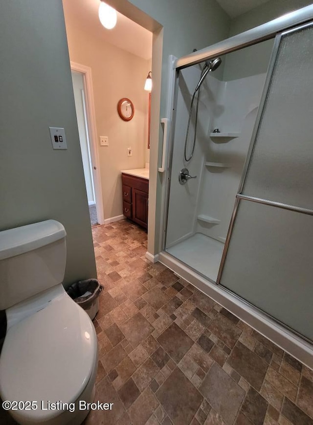 bathroom with vanity, toilet, and a shower with door