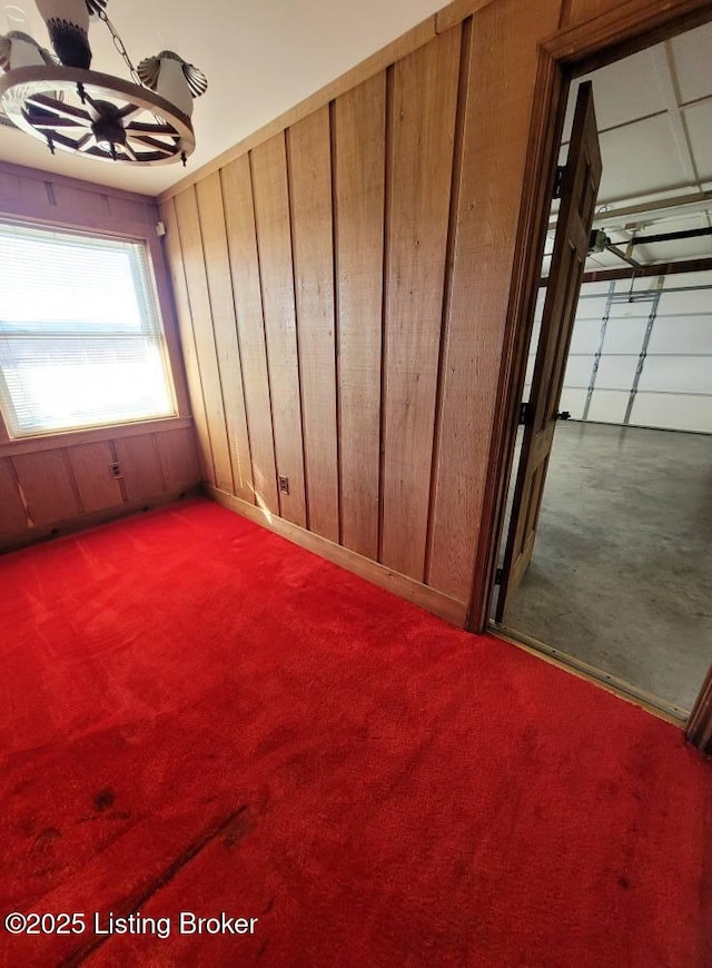 carpeted empty room featuring wood walls