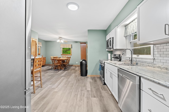 kitchen featuring stainless steel appliances, backsplash, ceiling fan, and a sink