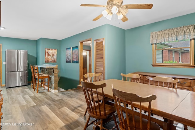 dining room featuring wood finished floors, a ceiling fan, and baseboards