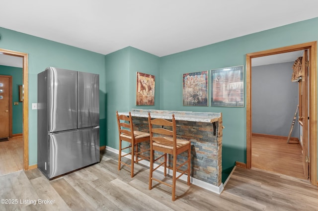 kitchen with baseboards, wood finished floors, and freestanding refrigerator