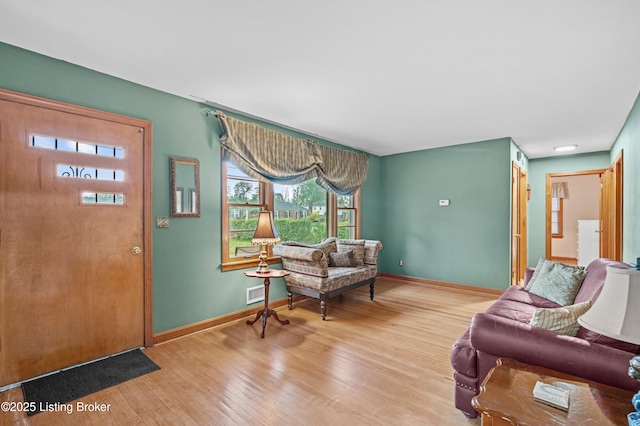 living area featuring baseboards, visible vents, and wood finished floors