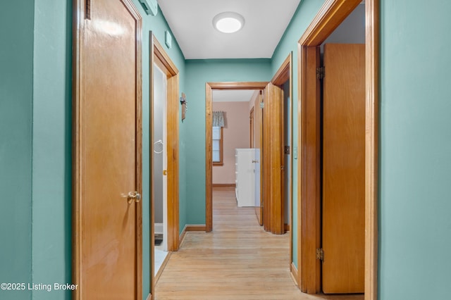 hall with light wood-style flooring and baseboards