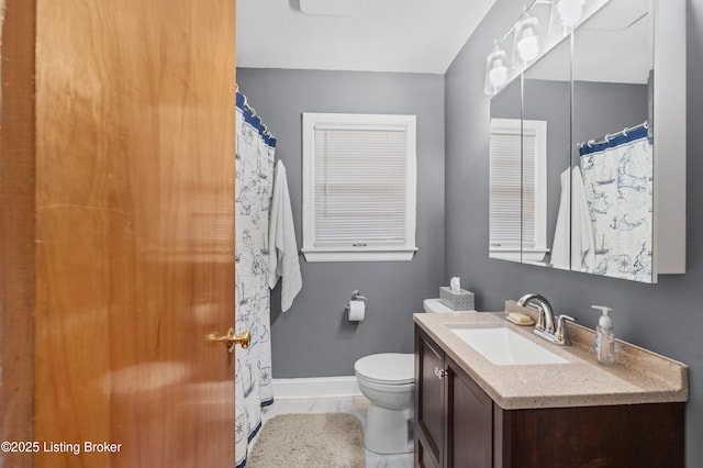 bathroom with toilet, vanity, and baseboards