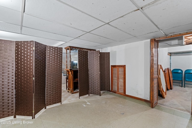 finished below grade area with tile patterned floors, a drop ceiling, and baseboards