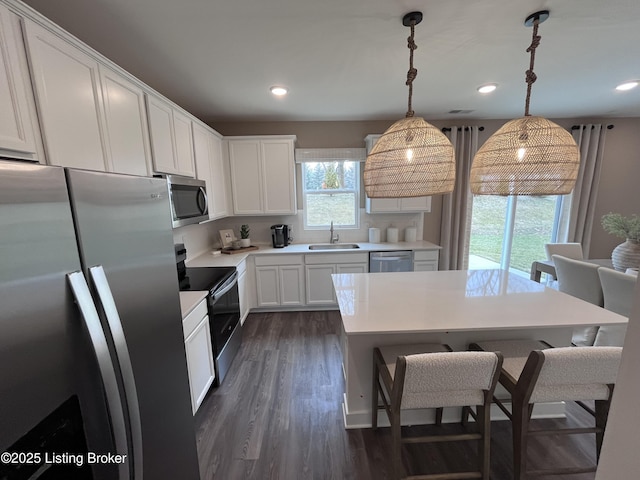 kitchen featuring appliances with stainless steel finishes, dark hardwood / wood-style floors, pendant lighting, sink, and white cabinets