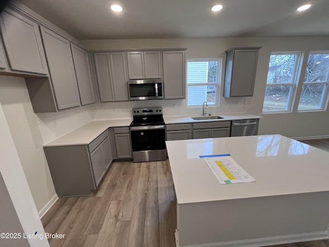 kitchen featuring gray cabinets, appliances with stainless steel finishes, sink, decorative backsplash, and light hardwood / wood-style flooring