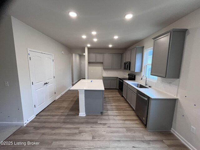 kitchen featuring gray cabinets, a kitchen island, sink, and appliances with stainless steel finishes