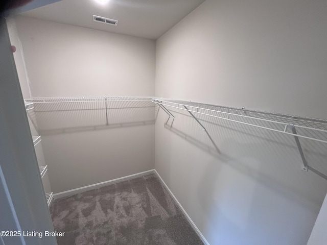 walk in closet featuring dark carpet