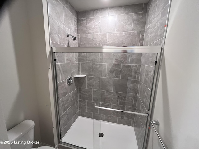 bathroom with a shower with door and toilet