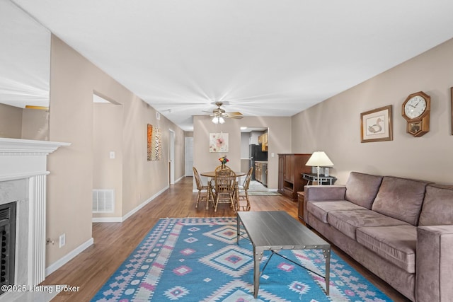 living room featuring hardwood / wood-style floors, a fireplace, and ceiling fan