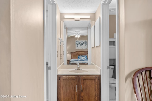 bathroom featuring vanity, ceiling fan, toilet, and a textured ceiling