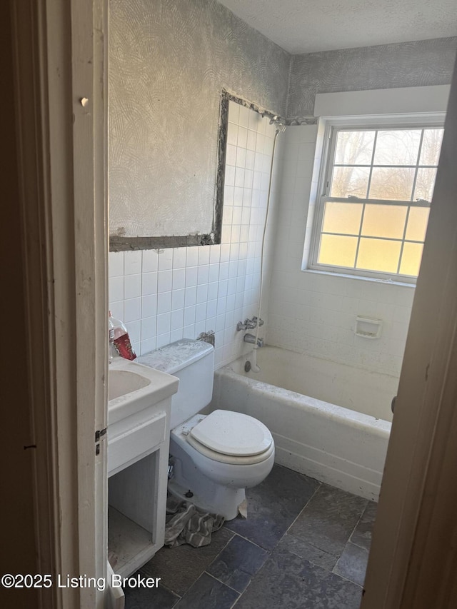 full bathroom with tiled shower / bath combo, vanity, tile walls, and toilet