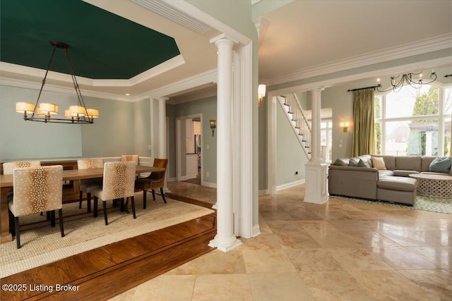 dining area featuring stairs, a raised ceiling, decorative columns, and crown molding