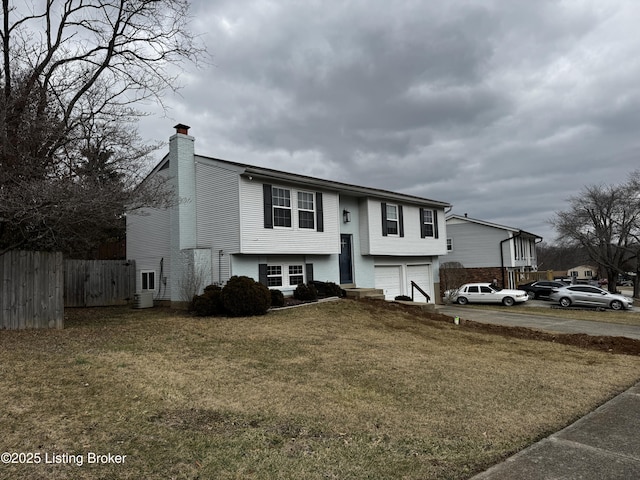 bi-level home with a garage, central AC unit, and a front yard