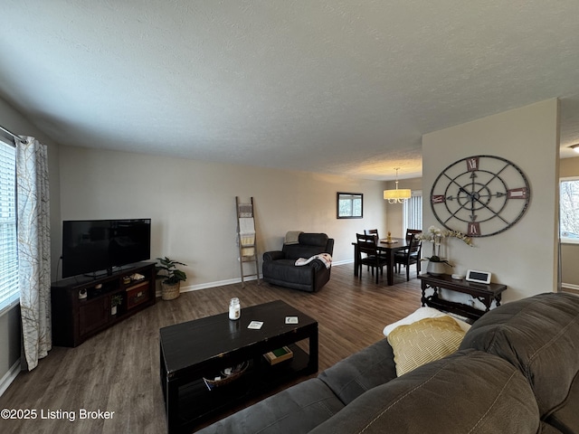 living room with a wealth of natural light, dark wood-type flooring, and a textured ceiling