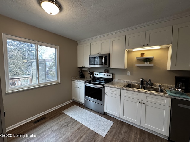 kitchen with sink, hardwood / wood-style floors, stainless steel appliances, a textured ceiling, and white cabinets