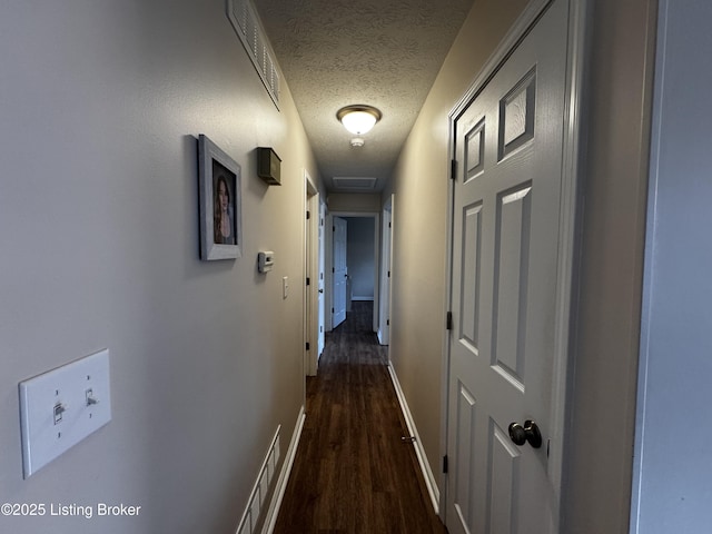 hall with dark hardwood / wood-style flooring and a textured ceiling