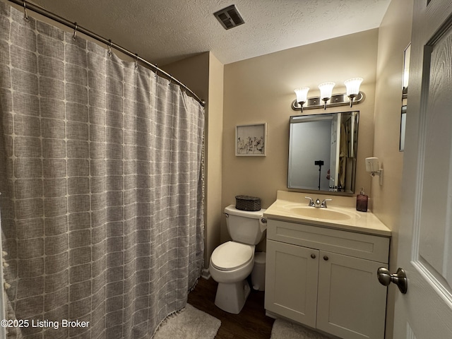 bathroom featuring vanity, wood-type flooring, toilet, and a textured ceiling